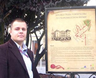 Adrian Wartecki z Działu Promocji Urzędu Miasta przy tablicy Miejskiej Trasy Turystycznej
